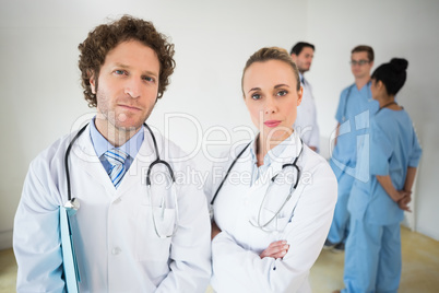 Confident doctors with colleagues in background