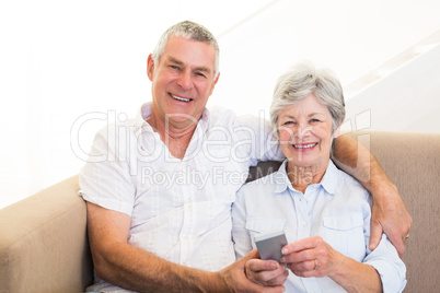 Smiling couple using mobile phone