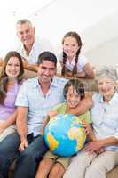 Smiling multigeneration family with globe