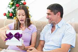 Surprised woman opening Christmas present