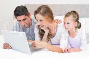 Family using laptop in bed