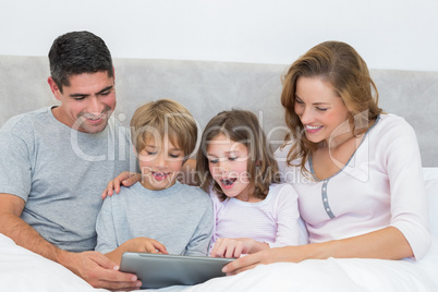 Family using digital tablet in bed