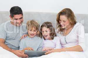 Family using digital tablet in bed