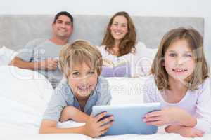 Smiling siblings holding digital tablet
