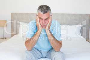 Sad senior man sitting on bed