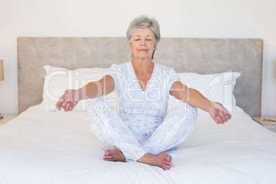 Senior woman meditating in bed