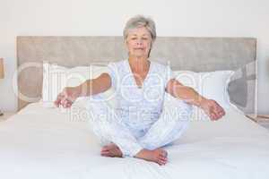 Senior woman meditating in bed