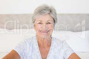 Happy senior woman sitting on bed