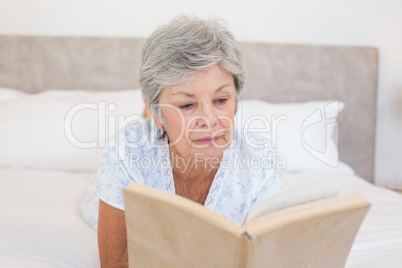 Senior woman reading story book in bed