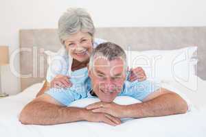 Senior woman lying on husband in bedroom