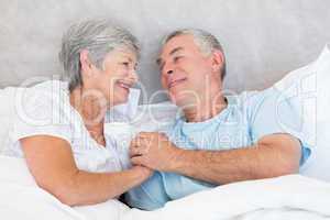 Senior couple holding hands in bed