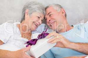 Senior couple exchanging gift box in bed
