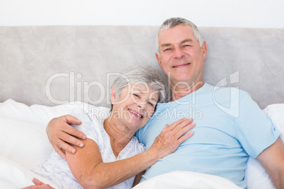 Senior man embracing woman in bed