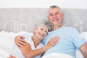 Senior man embracing woman in bed