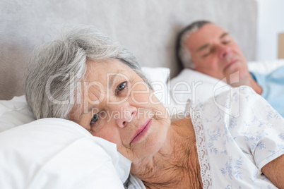 Senior woman lying with man in background