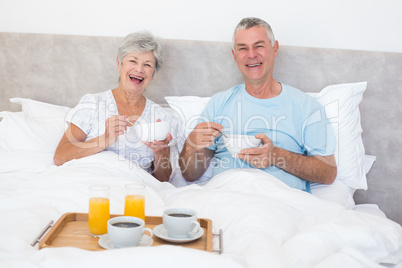 Happy senior couple having breakfast in bed
