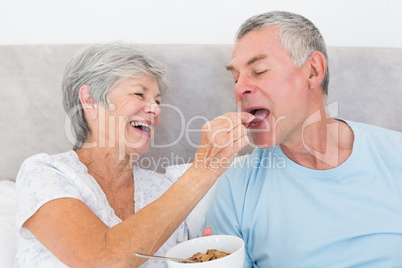 Loving senior woman feeding cereals to husband
