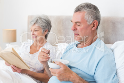 Senior couple with cereal bowl and book