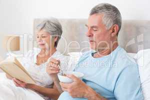 Senior couple with cereal bowl and book