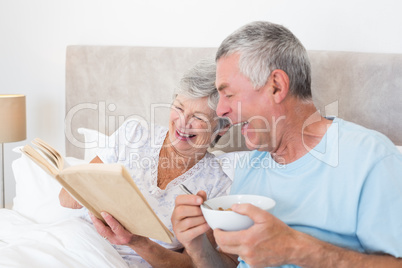 Senior couple reading book in bed