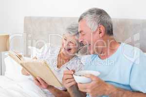Senior couple reading book in bed