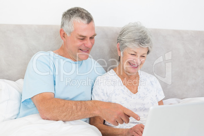 Senior couple using laptop in bed Senior couple using laptop in bed