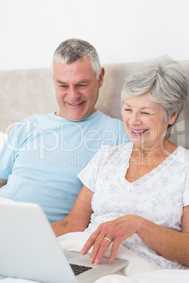 Senior couple using laptop computer in bed