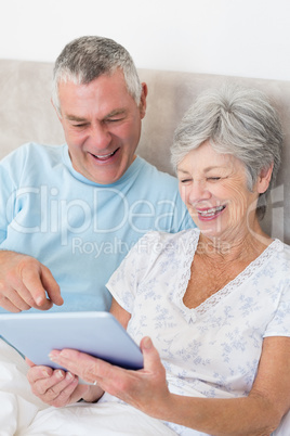 Senior couple using digital tablet in bed