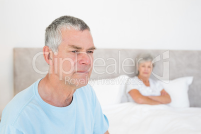 Sad senior man with woman in background