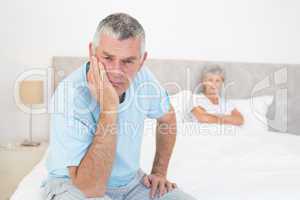 Sad senior man with woman in bed