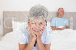 Sad senior woman with husband in bed