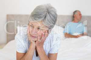 Sad senior woman with husband on bed
