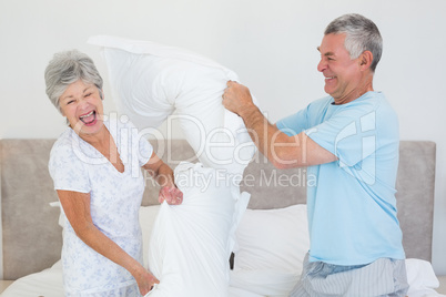 Senior couple having pillow fight in bed