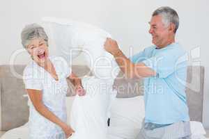 Senior couple having pillow fight in bed