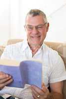 Senior man holding book on sofa