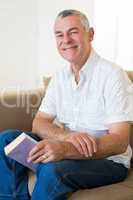 Senior man with book siting on sofa