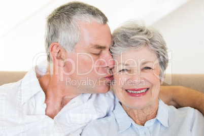 Senior man kissing wife on cheeks