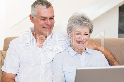 Senior couple using laptop on sofa