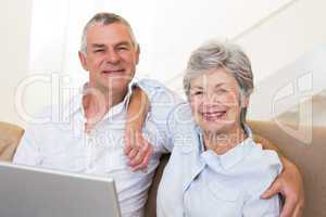 Senior couple with laptop on sofa