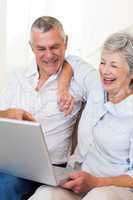 Happy senior couple looking at laptop