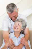 Senior man hugging wife sitting on sofa