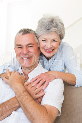 Senior woman embracing husband in house