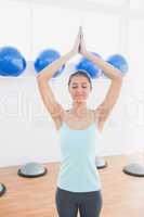 Sporty woman with joined hands in fitness studio