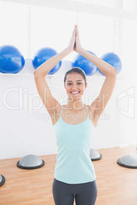 Beautiful woman with joined hands in fitness studio