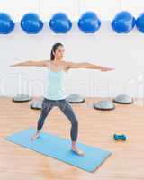 Sporty young woman stretching hands in fitness studio