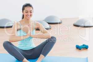 Beautiful sporty woman with joined hands in fitness studio