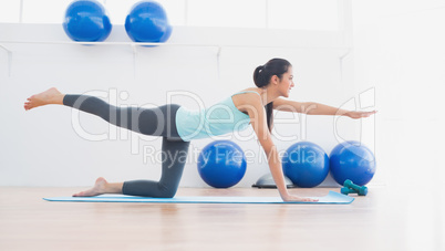 Sporty woman stretching hand and leg in fitness studio