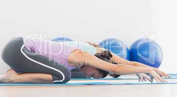 Two sporty women in meditation pose at fitness studio