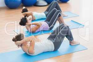 Determined women doing sit ups at fitness studio
