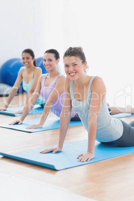 Smiling class doing the cobra pose in fitness studio